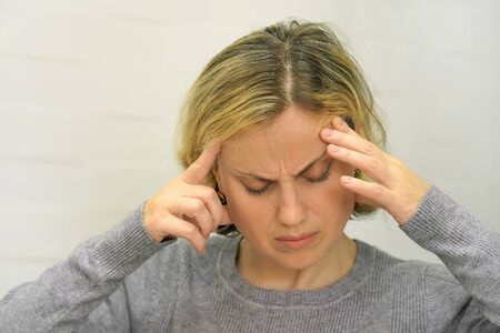 Woman suffering from headache migraine pain. Health problems, stress and depression. Female holds...