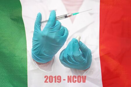 Hand of doctor or nurse in blue gloves holding syringe for vaccination against the background of the Italy flag. Medicine concept and fight the virus.の写真素材