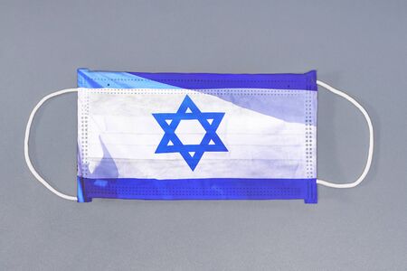 Isolated medical mask with flag of Israel on gray background. Closeup protective masks textile...