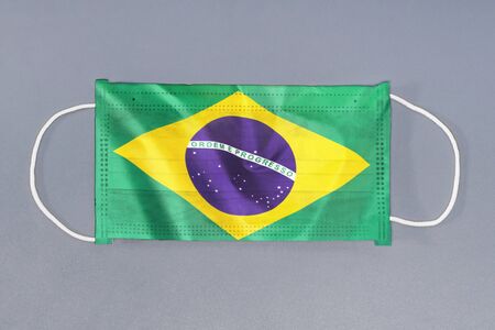 Isolated medical mask with flag of Brazil on gray background. Closeup protective masks textile filter. Health care and medical concept. Coronavirus, virus in Brazil.の写真素材