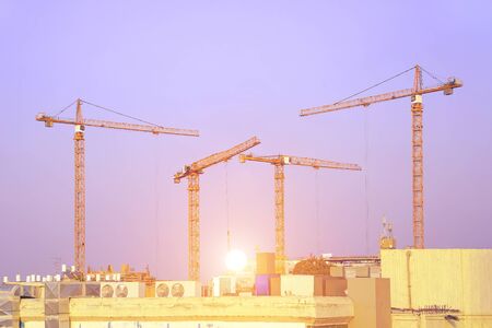 The construction of a skyscraper. Cranes and building structures. Construction site with cranes and a building against the backdrop of the dawn of the sky.の写真素材