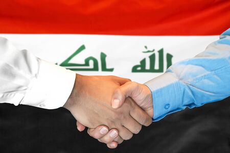 Business handshake on Iraq flag background. Men shaking hands and Iraq flag on background. Support conceptの写真素材
