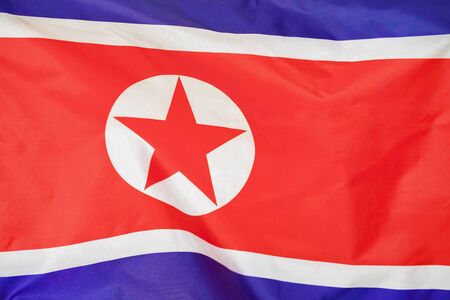 Fabric texture flag of North Korea. Flag of North Korea waving in the wind. North Korea flag is depicted on a sports cloth fabric with many folds. Sport team banner.の写真素材