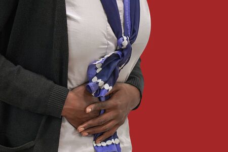 Abdominal pain. Closeup of african woman suffering from abdominal pain at home. Concept of...