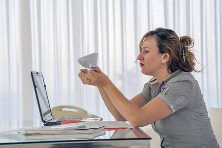Portrait of office worker woman vomits letter, document. Woman reads negative news in a letter. Shocked beauty girl business manager received layoff message letter from company feeling surprised.の写真素材