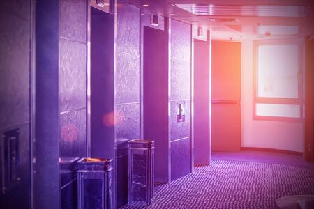 View of 4 elevator doors in a hotel at sunset through a window. Wide viewing angle of several modern elevators with closed doors in the evening. Elevators in the modern lobby of an office building.の写真素材