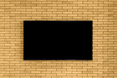 Blank black tv on the brown brick wall with copy space. TV display on old brick wall background....
