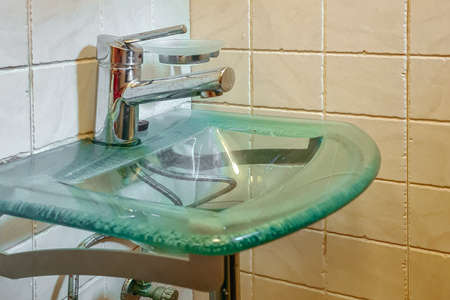 Green tempered glass bowl hand wash basin in home. Washbasin interior sink with modern design. Close-up of bathroom.の写真素材