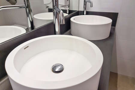 Modern white bathroom sink with faucet. Bathroom interior sink with modern design in luxury hotel.の写真素材