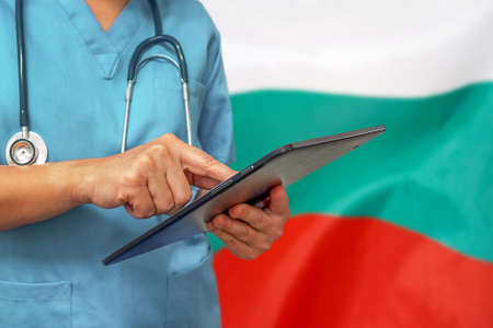 Surgeon or doctor using a digital tablet on the background of the Bulgaria flag. Medical equipment or medical network, technology and diagnostics in Bulgaria.の写真素材