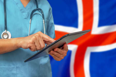 Surgeon or doctor using a digital tablet on the background of the Iceland flag. Medical equipment or medical network, technology and diagnostics in Iceland.の写真素材