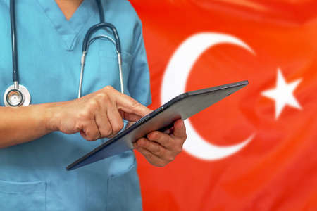 Surgeon or doctor using a digital tablet on the background of the Turkey flag. Medical equipment or medical network, technology and diagnostics in Turkey.の写真素材