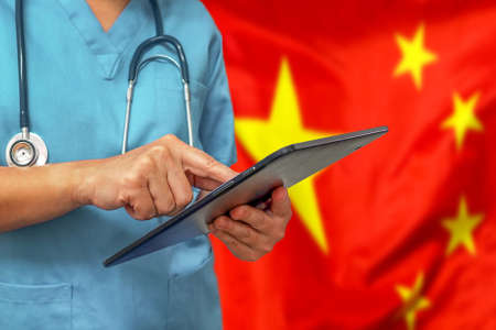 Surgeon or doctor using a digital tablet on the background of the China flag. Medical equipment or medical network, technology and diagnostics in China.の写真素材