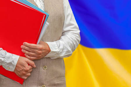 Woman holding red folder on Ukraine flag background. Education and jurisprudence concept in Ukraineの写真素材