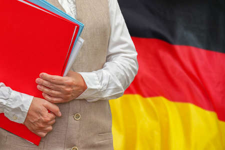 Woman holding red folder on Germany flag background. Education and jurisprudence concept in Germanyの写真素材