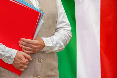 Woman holding red folder on Italy flag background. Education and jurisprudence concept in Italyの写真素材