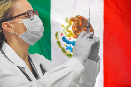 Female doctor or nurse in gloves holding syringe for vaccination against the background of the Mexico flag. Medicine concept and fight the virus. Coronavirus in Mexico.の写真素材