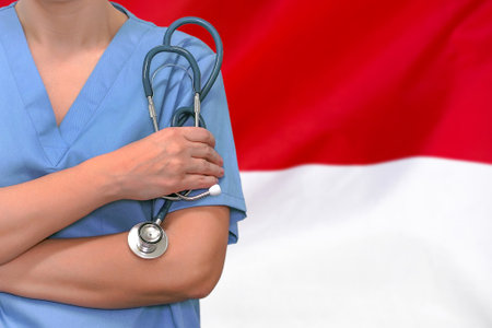 Female surgeon or doctor with stethoscope in hand on the background of the Indonesia flag. Surgery concept in Indonesiaの写真素材
