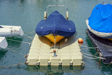 Small motor boat at anchor by rope in pierの写真素材