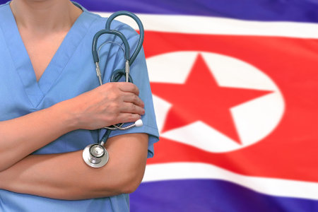 Female surgeon or doctor with stethoscope in hand on the background of the North Korea flag. Surgery concept in North Koreaの写真素材