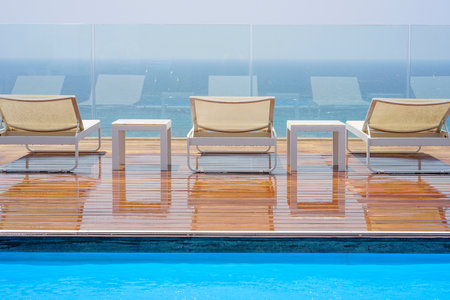 Three loungers, standing and table on a wooden floor on the background of the seaのeditorial素材