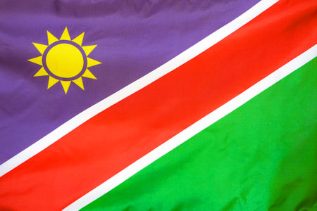 Fabric texture flag of Namibia. Flag of Namibia waving in the wind. Namibia flag is depicted on a sports cloth fabric with many folds. Sport team banner.の写真素材
