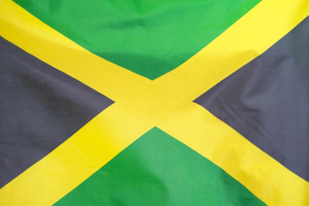 Fabric texture flag of Jamaica. Flag of Jamaica waving in the wind. Jamaica flag is depicted on a sports cloth fabric with many folds. Sport team bannerの写真素材