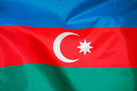 Fabric texture flag of Azerbaijan. Flag of Azerbaijan waving in the wind. Azerbaijan flag is depicted on a sports cloth fabric with many folds. Sport team bannerの写真素材