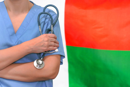 Female surgeon or doctor with stethoscope in hand on the background of the Madagascar flag. Surgery concept in Madagascarの写真素材