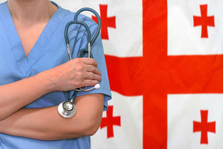Female surgeon or doctor with stethoscope in hand on the background of the Georgia flag. Surgery concept in Georgiaの写真素材