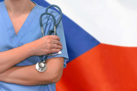 Female surgeon or doctor with stethoscope in hand on the background of the Czech Republic flag. Surgery concept in Czech Republicの写真素材
