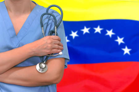 Female surgeon or doctor with stethoscope in hand on the background of the Venezuela flag. Surgery concept in Venezuelaの写真素材