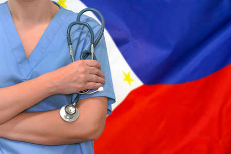 Female surgeon or doctor with stethoscope in hand on the background of the Philippines flag. Surgery concept in Philippinesの写真素材