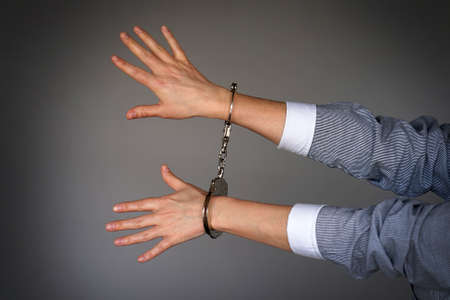 Arrested woman handcuffed hands. Prisoner or arrested terrorist, close-up of hands in handcuffs isolated. Criminal female hands locked in handcuffsの写真素材