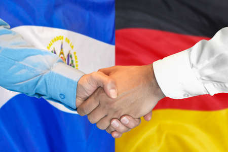 Business handshake on the background of two flags. Men handshake on the background of the El Salvador and Germany flag. Support concept.の写真素材