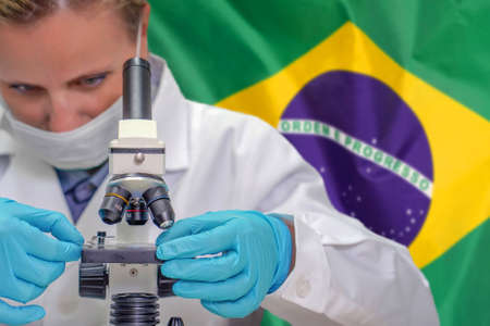 Female biochemist looking through a microscope against Brazil flag background. Medical technology and pharmaceutical research and development of science concept in Brazilの写真素材
