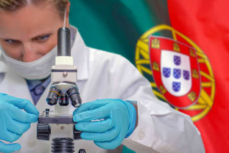 Female biochemist looking through a microscope against Portugal flag background. Medical technology and pharmaceutical research and development of science concept in Portugalの写真素材