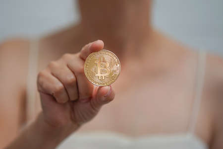 Woman holding a Bitcoin token. Cryptocurrency is a virtual or digital money. Woman holds a gold coin in her hands bitcoin. Mining cryptocurrency conceptの写真素材