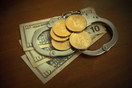 Golden Bitcoins Cryptocurrency with Handcuffs on Dollar bills. Digital crime, arrest or hacking concept. Handcuffs dollars and bitcoins on the table. Not legal miningの写真素材
