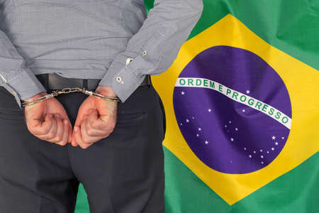 Male with handcuffs on the background of the Brazil flag. back view. Concept of prisons and corruption in Brazilの写真素材