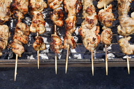 Grilling shashlik on barbecue grill. Skewered chicken satay roasted on smoky charcoal grillの写真素材