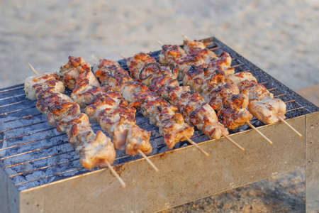 Grilling shashlik on barbecue grill. Closeup delicious chicken breast on barbeque grill. Skewered chicken satay roasted on smoky charcoal grillの写真素材