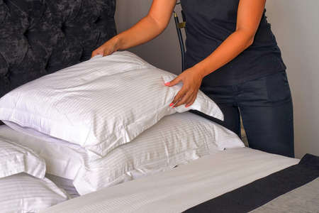 Hand of young woman maid making bed in hotel room. Housekeeper Making Bedの写真素材