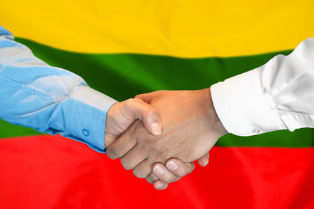 Business handshake on Lithuanian flag background. Men shaking hands and Lithuanian flag on background. Support conceptの写真素材