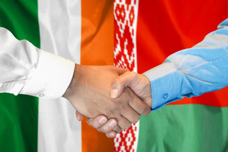 Business handshake on background of two flags. Men's handshake on the background of Ireland and Belarus flag. Support conceptの写真素材
