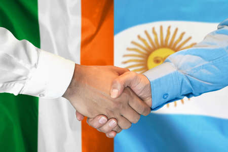 Business handshake on background of two flags. Men handshake on background of Ireland and Argentina flag. Support conceptの写真素材