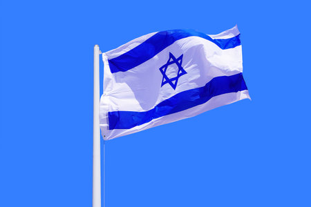 Israel flag waving against clean blue sky, close up. Israel flag in the blue sky. Flag Israel on blue sky backgroundの写真素材