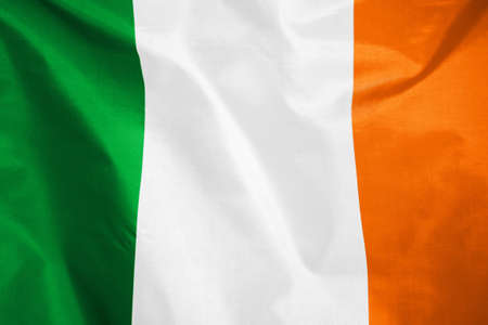 Fabric texture flag of Ireland. Flag of Ireland waving in the wind. Ireland flag is depicted on a sports cloth fabric with many folds. Sport team banner.の写真素材