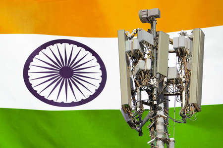 Telecommunications tower with a 5G cellular network antenna agains flag of India. Telecommunication...