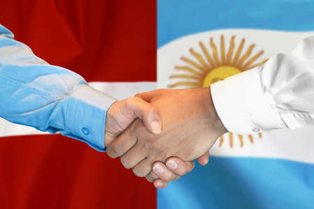 Business handshake on background of two flags. Men handshake on background of Argentina and Latvia flag. Support conceptの写真素材